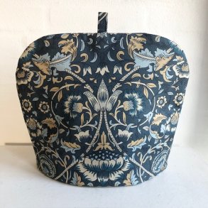 Tehtte i bomuldsstof med en petroliumsfarvet bund og motiver af blomster og blade.