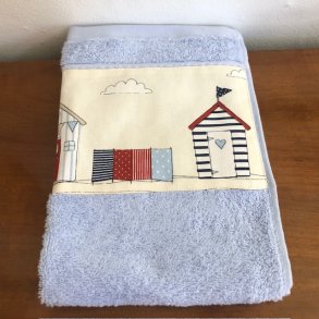 Gstehndklde i lys bl med en bort af farvestrlende badehuse forneden.