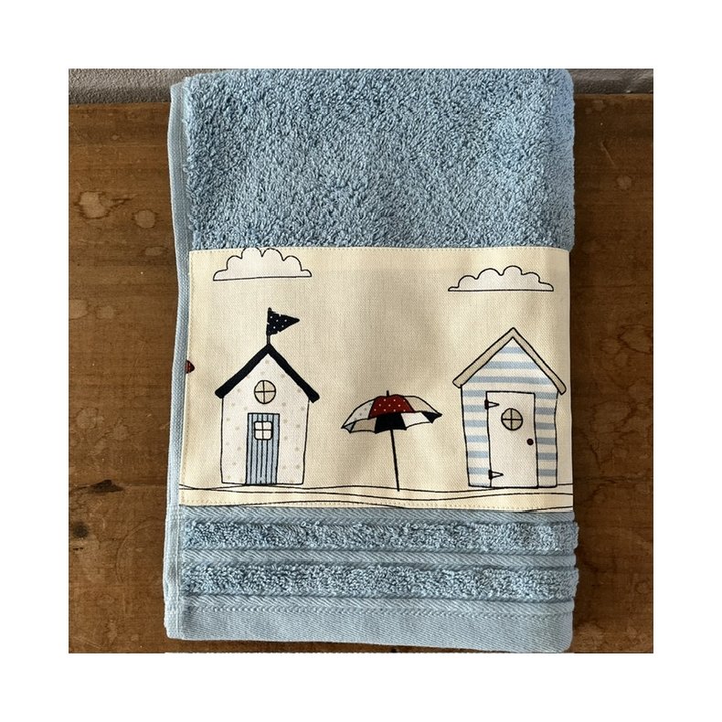 G�steh�ndkl�de i lys bl� med en bort af farvestr�lende badehuse forneden.