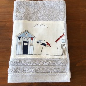 Gstehndklde i en sart lys gr farve med en bort af sm farvestrlende badehuse.