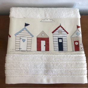 Hndklde i cream med en bort af badehuse forneden.