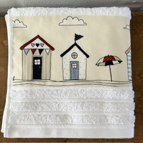 H�ndkl�de i hvid med en bort af badehuse forneden.