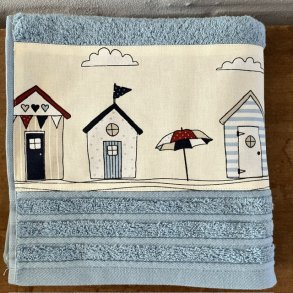 H�ndkl�de i lys bl� bomuld med en bort af forskellige badehuse.