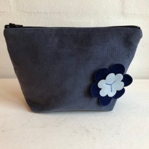 Kosmetikpung-makeuptaske i stvet blt fljl med blomst.