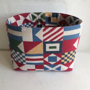 Brdkurv , opbevaringskurv i gobelin med motiver af signalflag i mange farver.