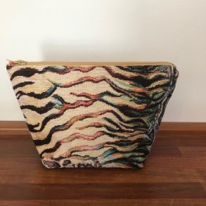 Kosmetikpung , makeuptaske i kraftigt lyst stof med motiver af dyreprint.