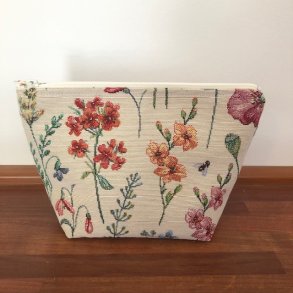 Kosmetikpung , makeuptaske i lyst kraftigt stof med blomster i forskellige farver.