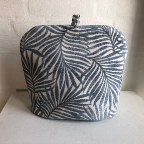 Tehtte i et kraftigt lyst stof med bl blade, som er fremhvede.