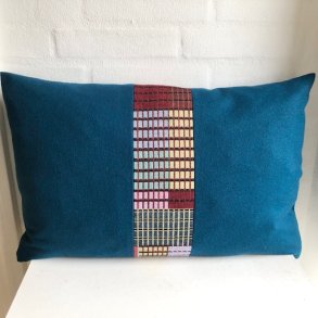 Designpude i ensfarvet petroliumsfarvet uld med m�nstret stribe imidten