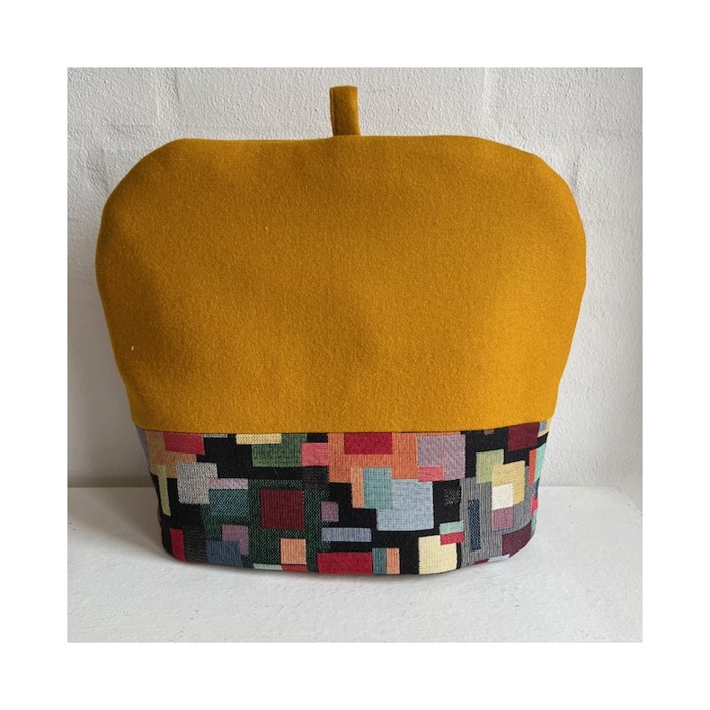 Tehtte i karrygul uld med kant af farvestrlende gobelin forneden.