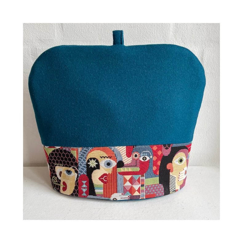 Tehtte , tevarmer i petroliumsfarvet uld foroven og med en farvestrlende gobelinkant forneden.