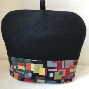 Tehtte i sort uld med en kant i gobelin med motiver af firkanter.