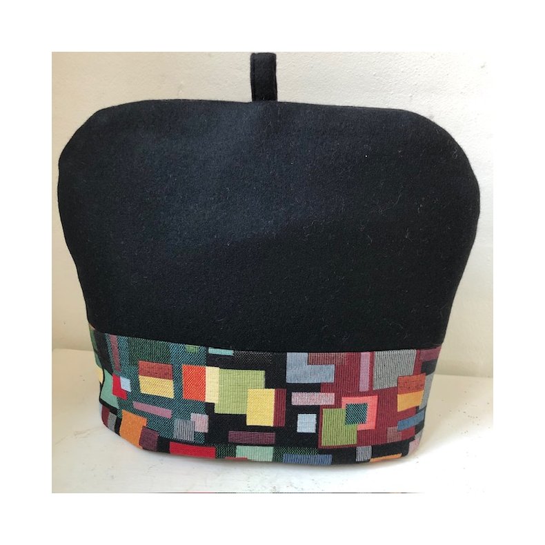 Tehtte i sort uld med en kant i gobelin med motiver af firkanter.