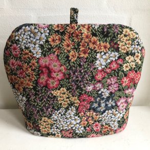 Tehtte i et stof med sort bund og blomster i mange farver